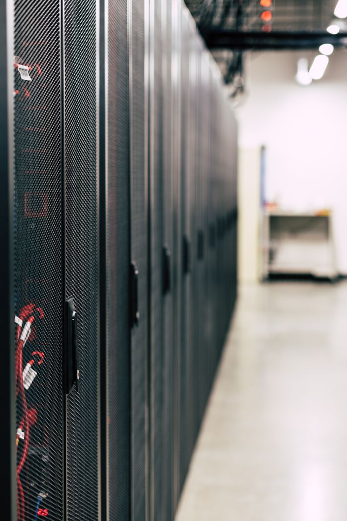 team-02 Metal black cabinets with servers inside with red wires connected standing in row in lighted room