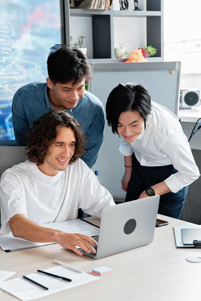 Diverse team of young professionals collaborating around a laptop at a stylish office.